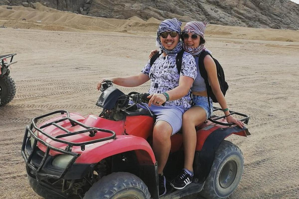 dues persones assegudes en un quad al desert