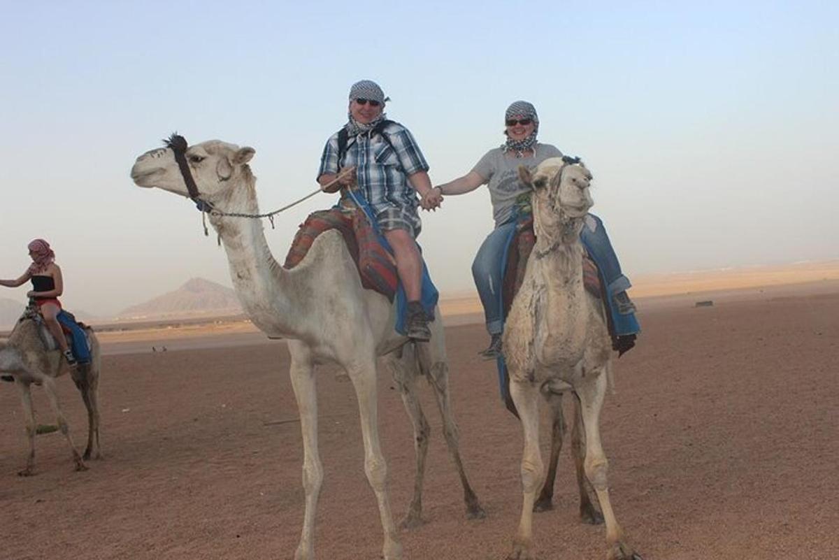tres persones muntades en camells al desert
