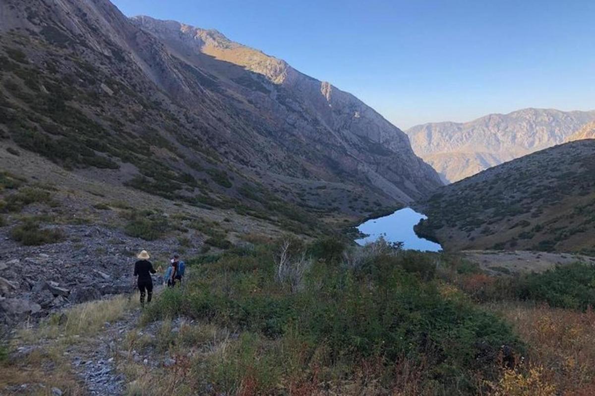 two people walking on a trail in a mountain