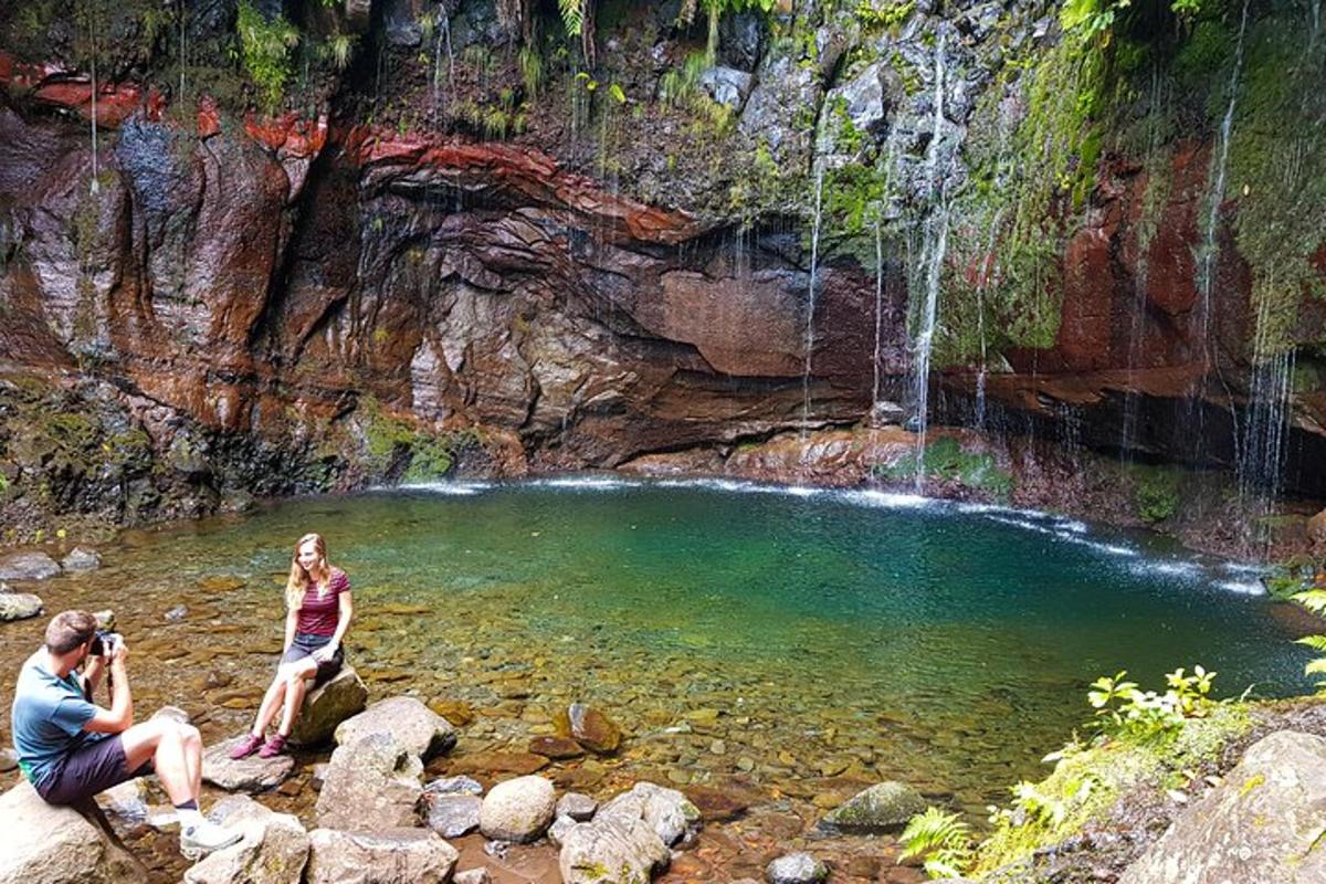 un home i una dona drets en un bassal d'aigua amb una cascada
