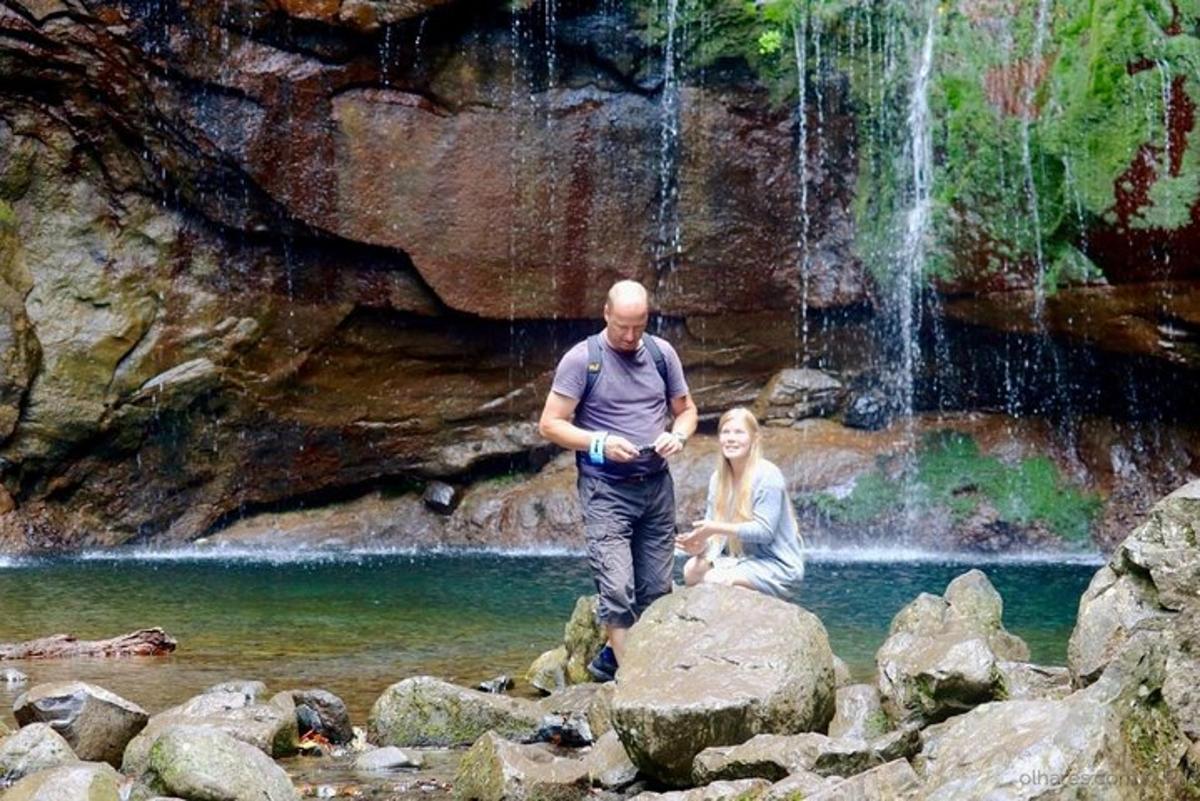 un uomo e una donna in piedi sulle rocce di fronte a una cascata