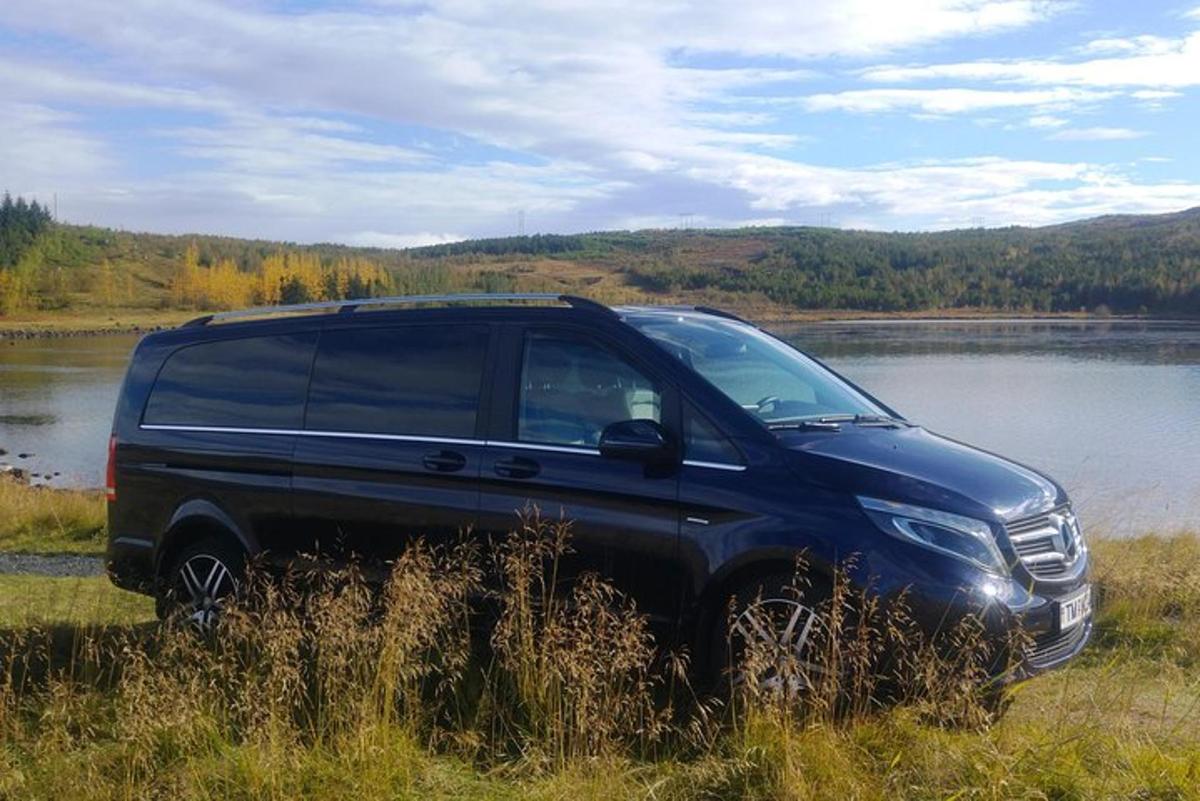 Svartur jeppabíll lagður á túni við stöðuvatn