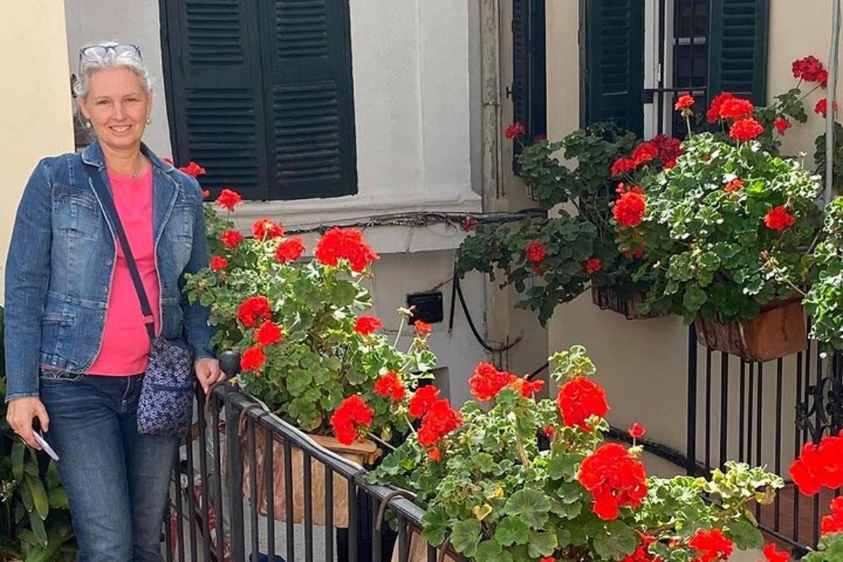 žena stojící na balkóně s červenými květinami