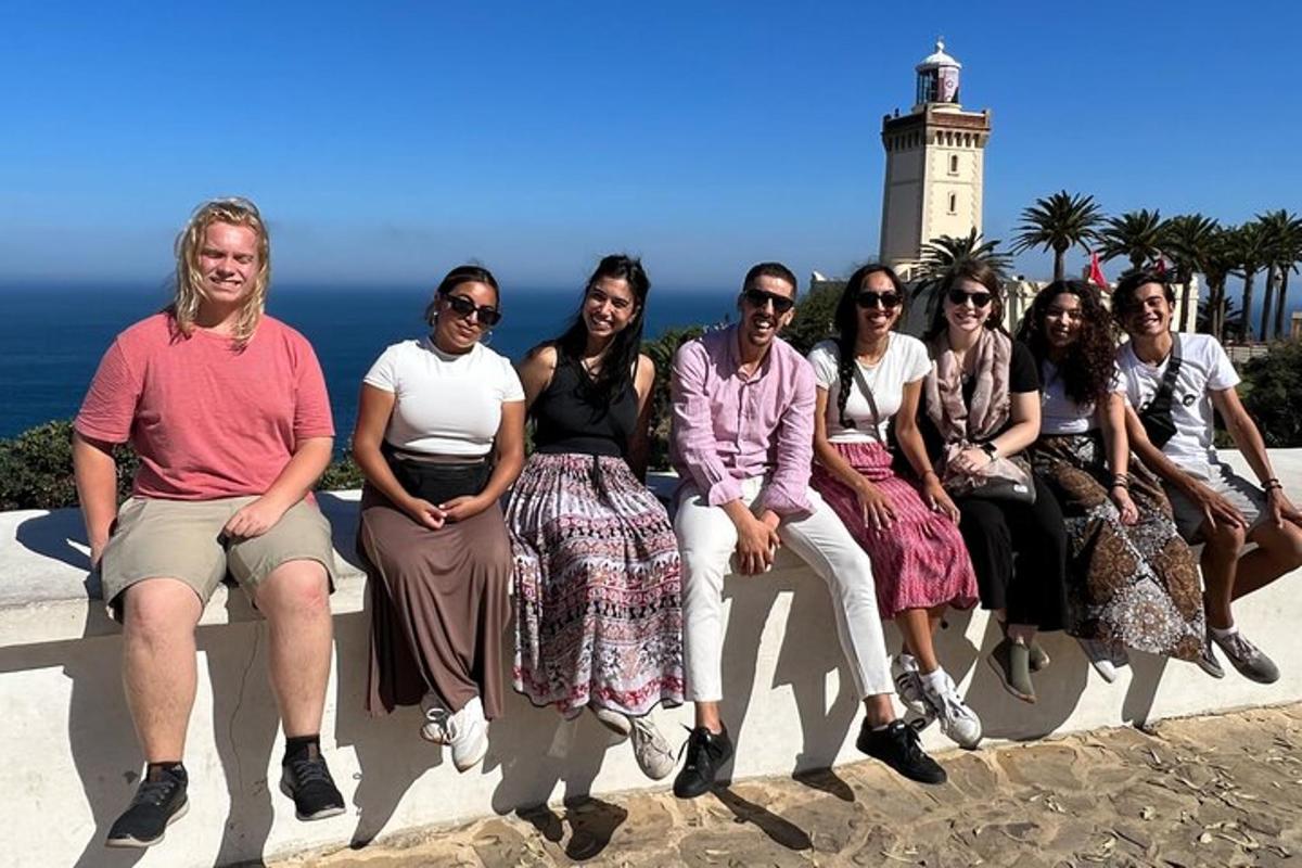 un grup de persones assegudes en un banc davant d'un far