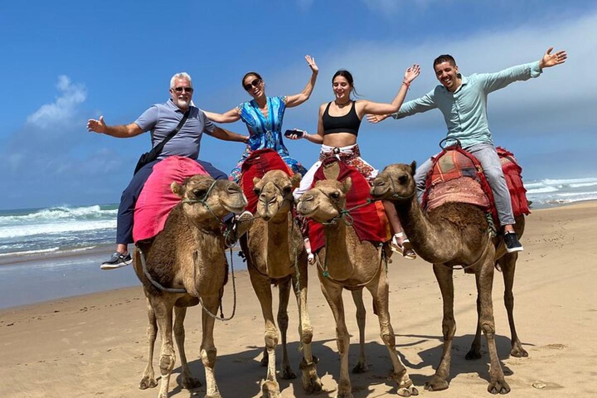 um grupo de pessoas andando de camelo na praia