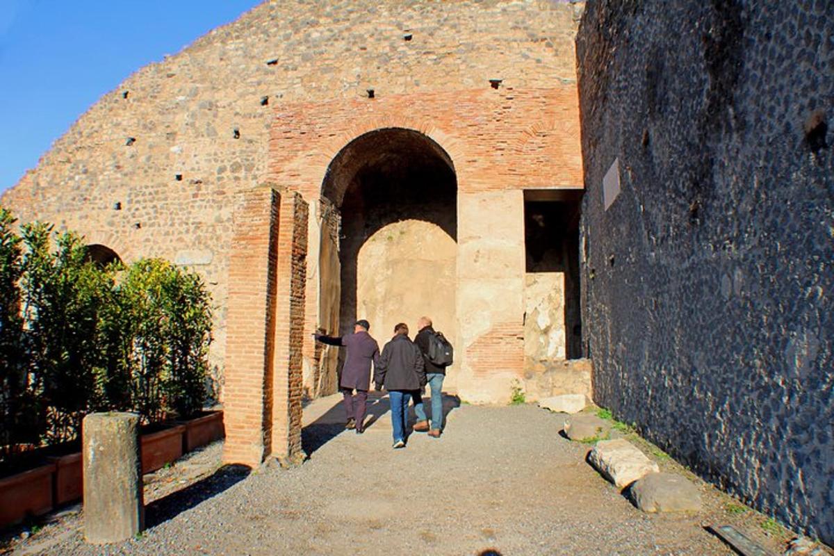 tre persone che camminano attraverso un arco in un edificio in mattoni