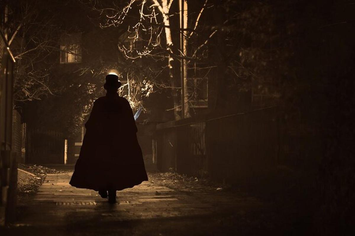 Una mujer con una capa caminando por una calle de noche