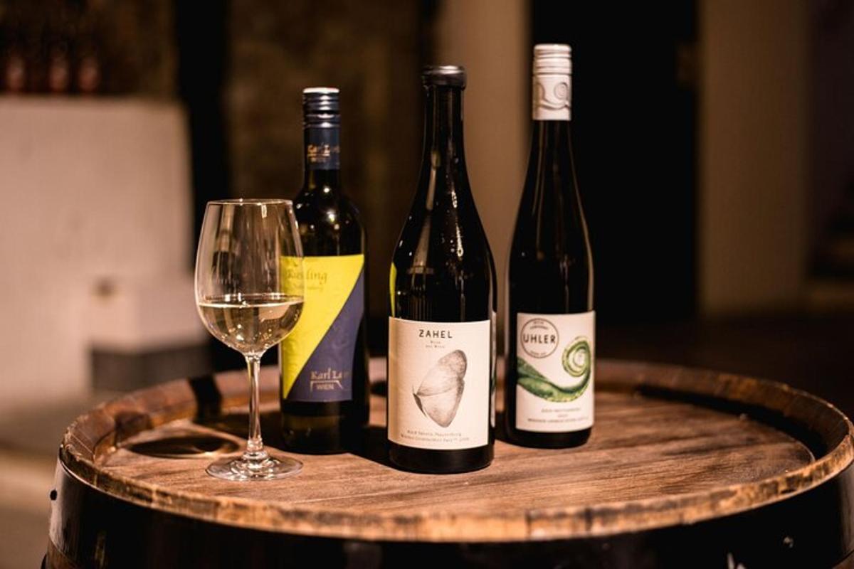 three bottles of wine and a glass on a barrel