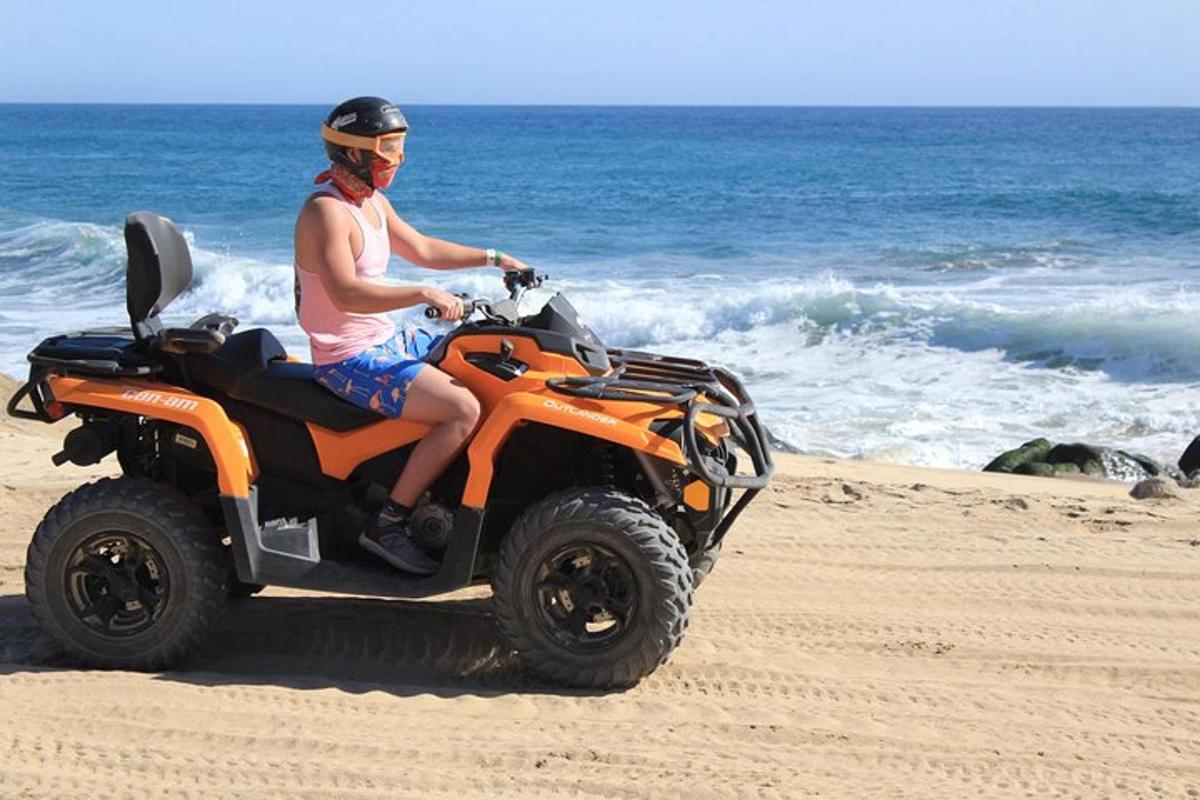 en mand kører på en orange ATV på stranden