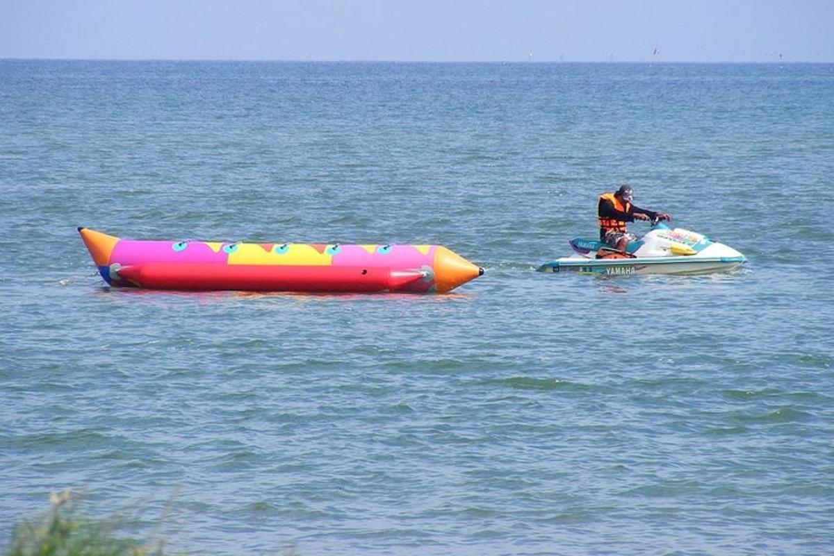 Un hombre está en una balsa en el agua junto a un inflable.