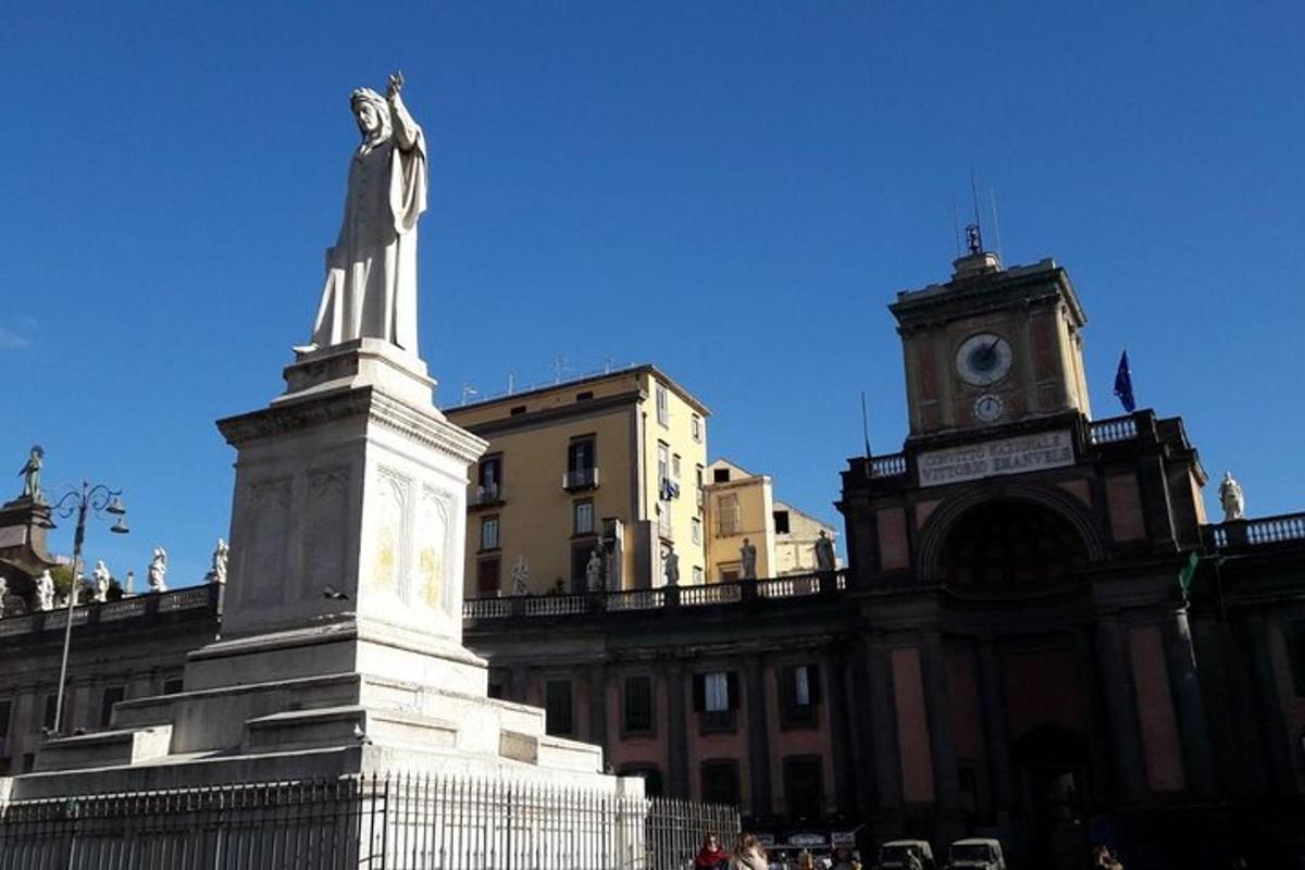 una estàtua davant d'un edifici amb una torre de rellotge