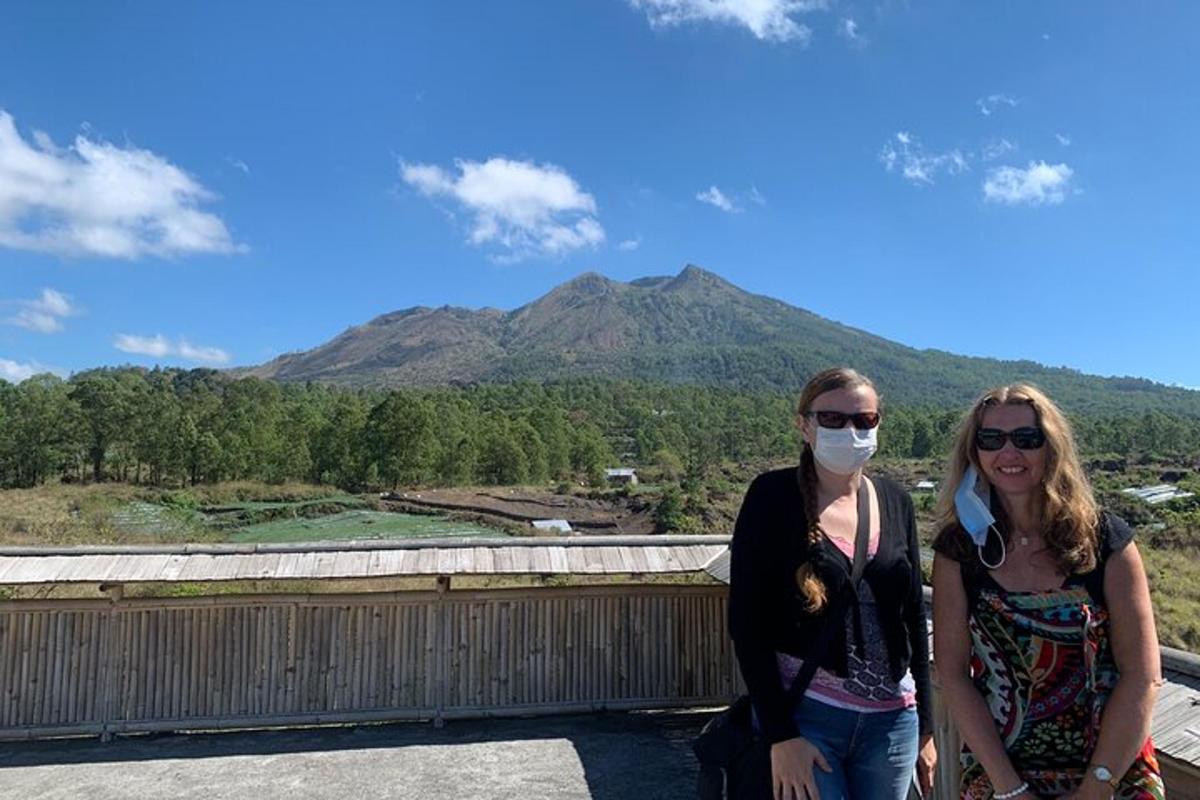 duas mulheres em pé em um telhado com uma montanha ao fundo