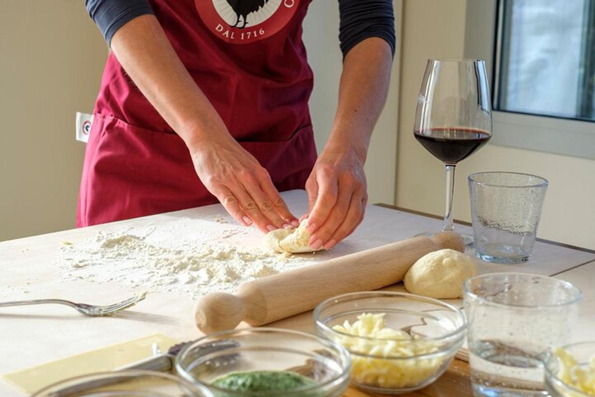 a woman kneading dough on a table with a glass of wine