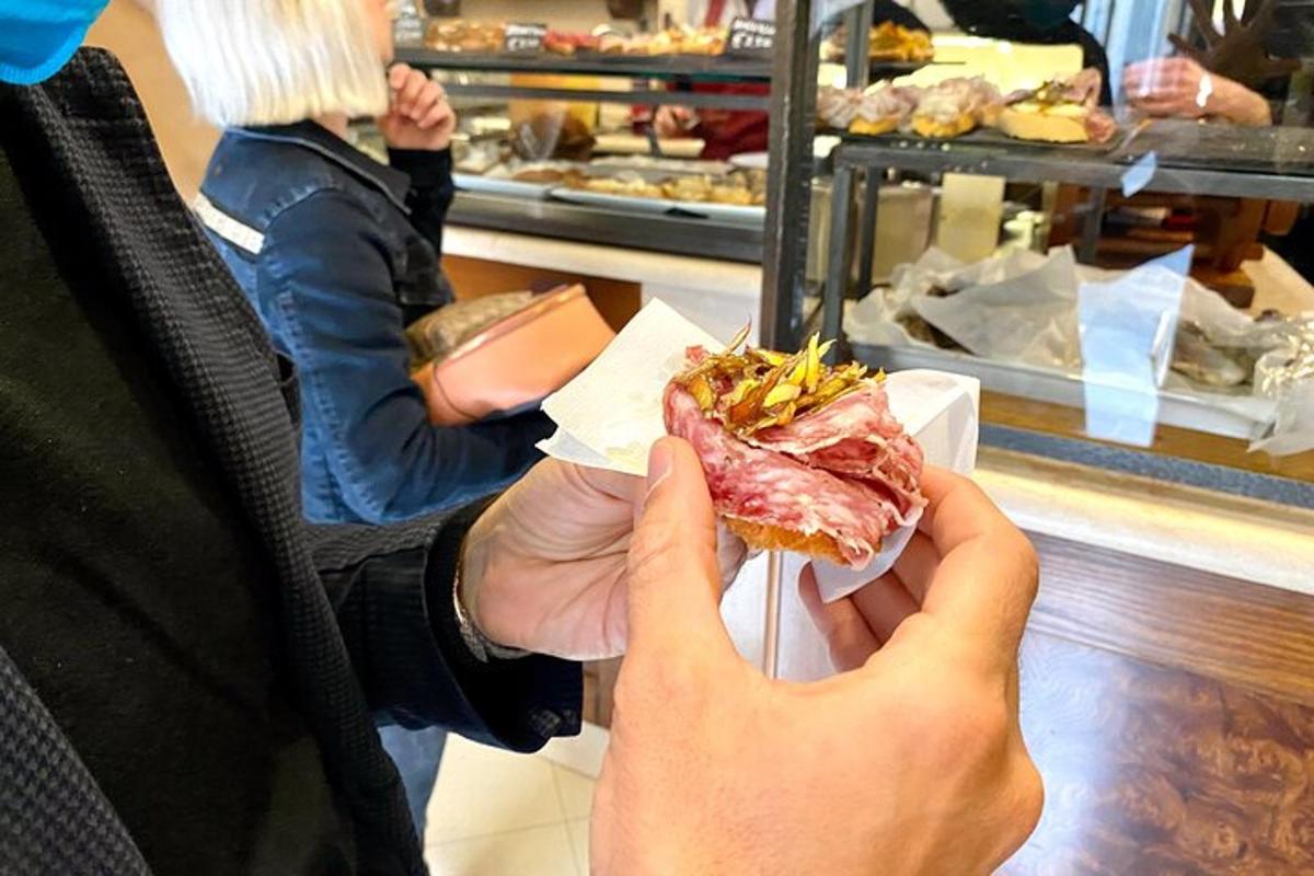 seseorang yang memegang sandwic di hadapan sebuah kedai