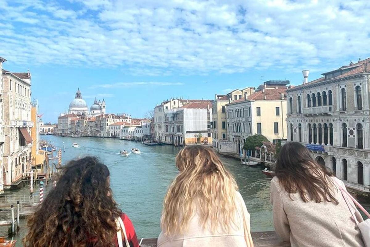 drie vrouwen staan op een brug en kijken naar een rivier
