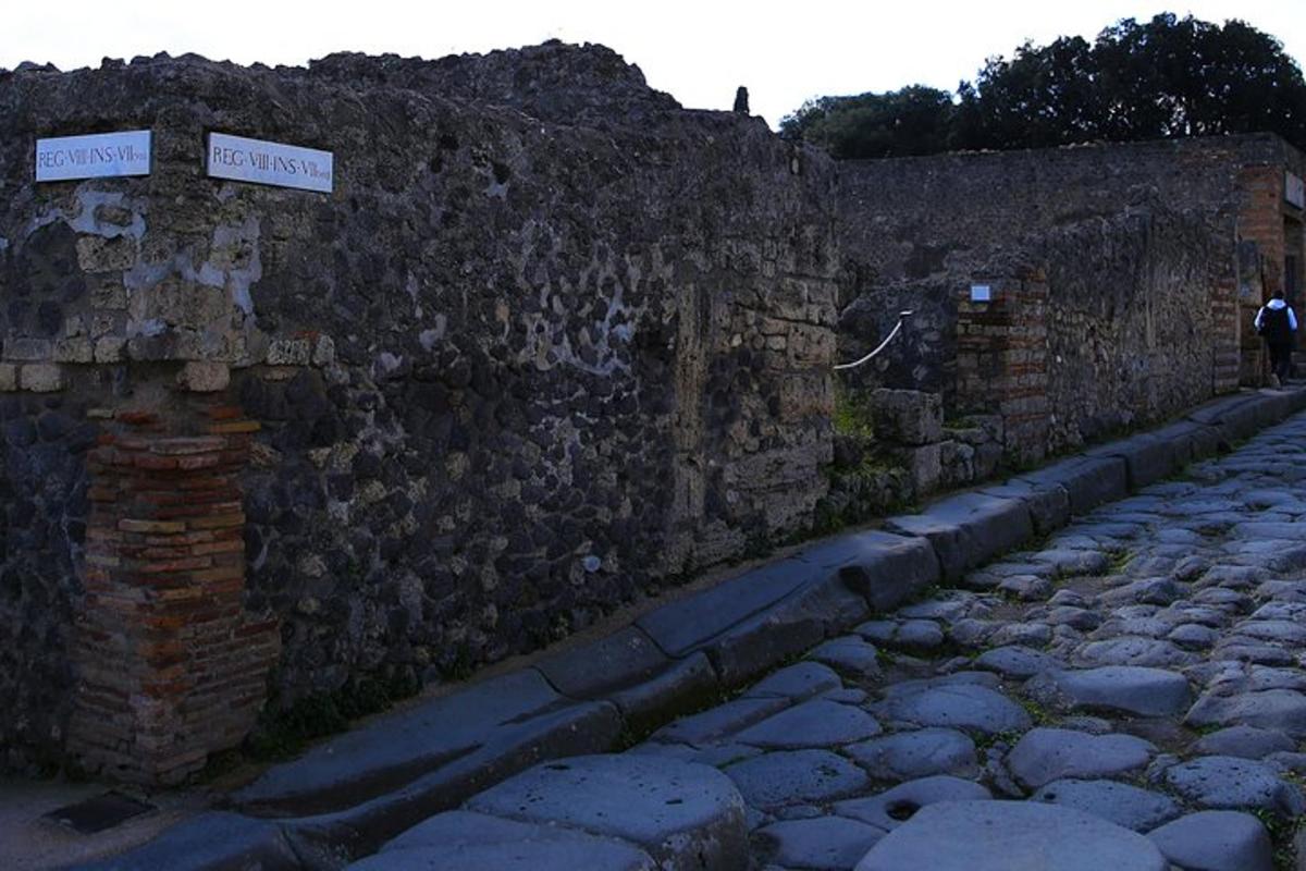 ένας πέτρινος τοίχος με δύο πινακίδες δρόμου πάνω του