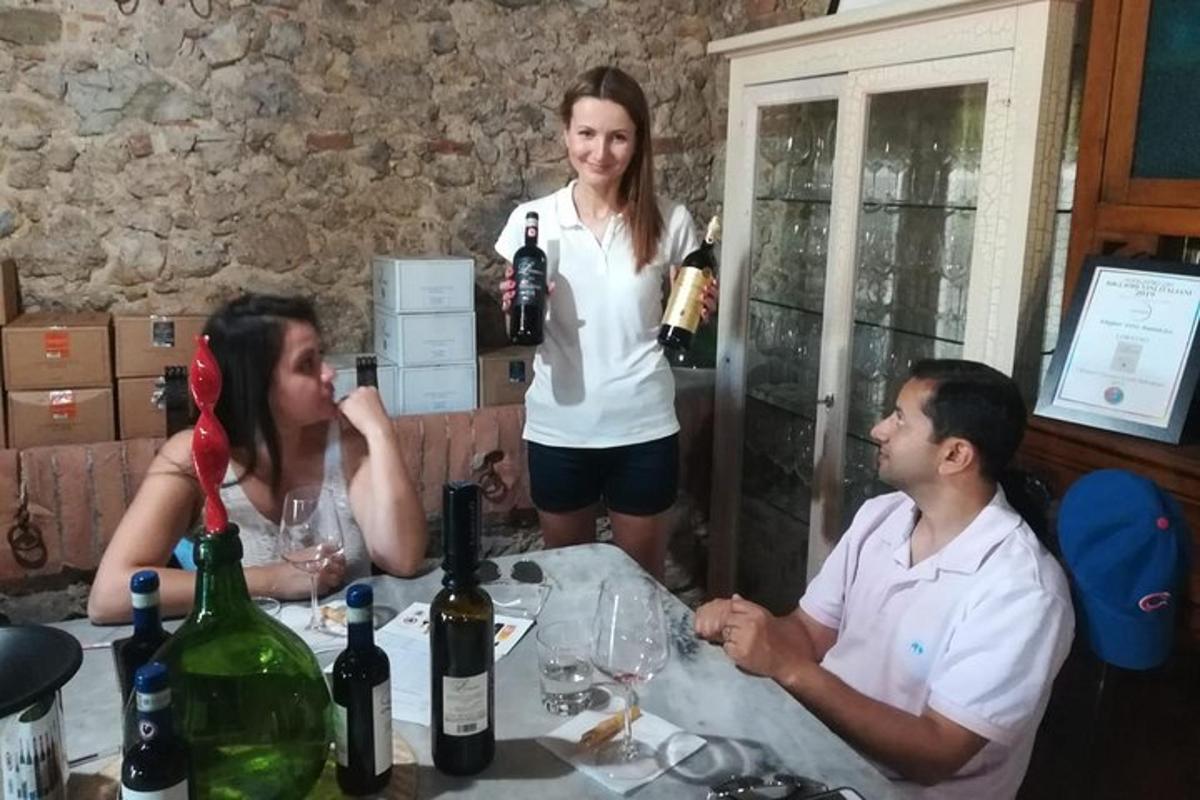 tre persone sedute a un tavolo con bottiglie di vino