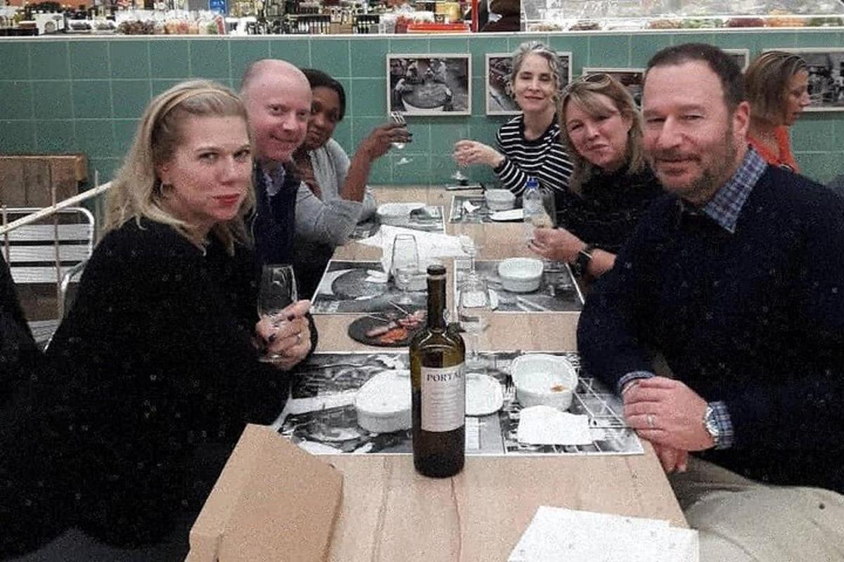 um grupo de pessoas sentadas ao redor de uma mesa com uma garrafa de vinho
