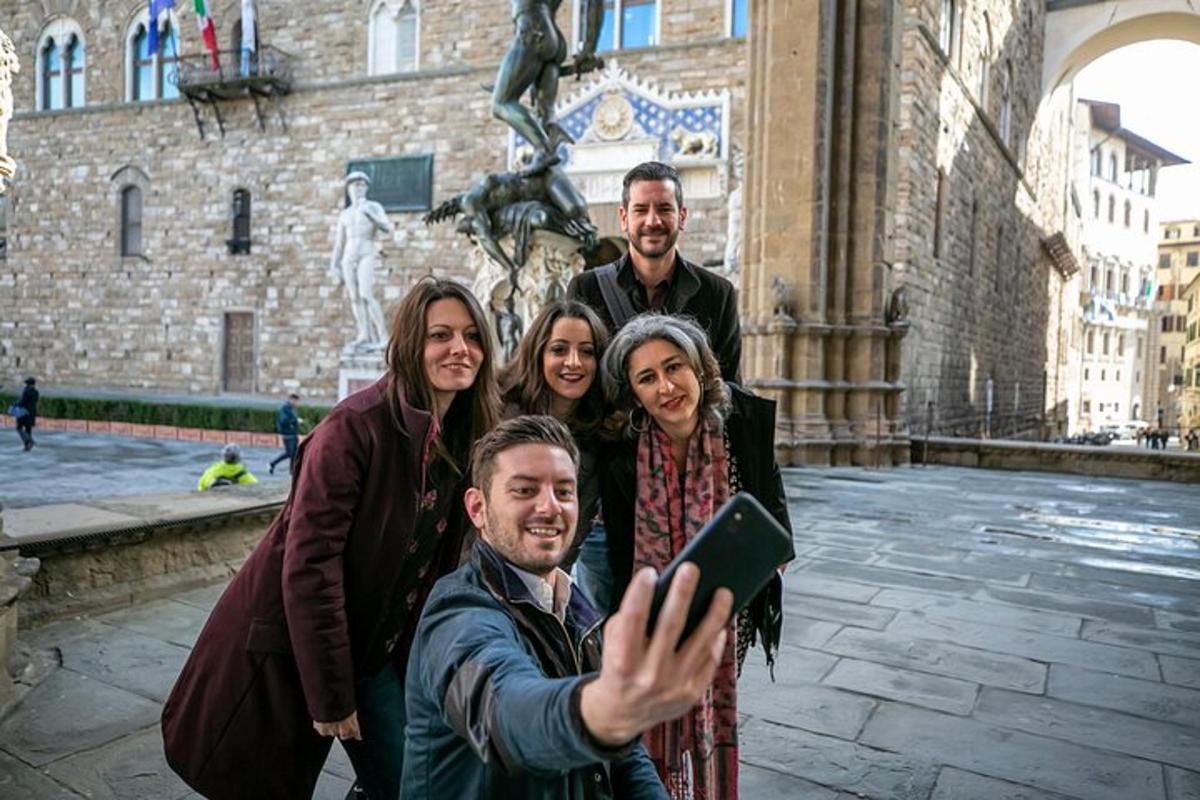 cilvēku grupa fotografējas ēkas priekšā