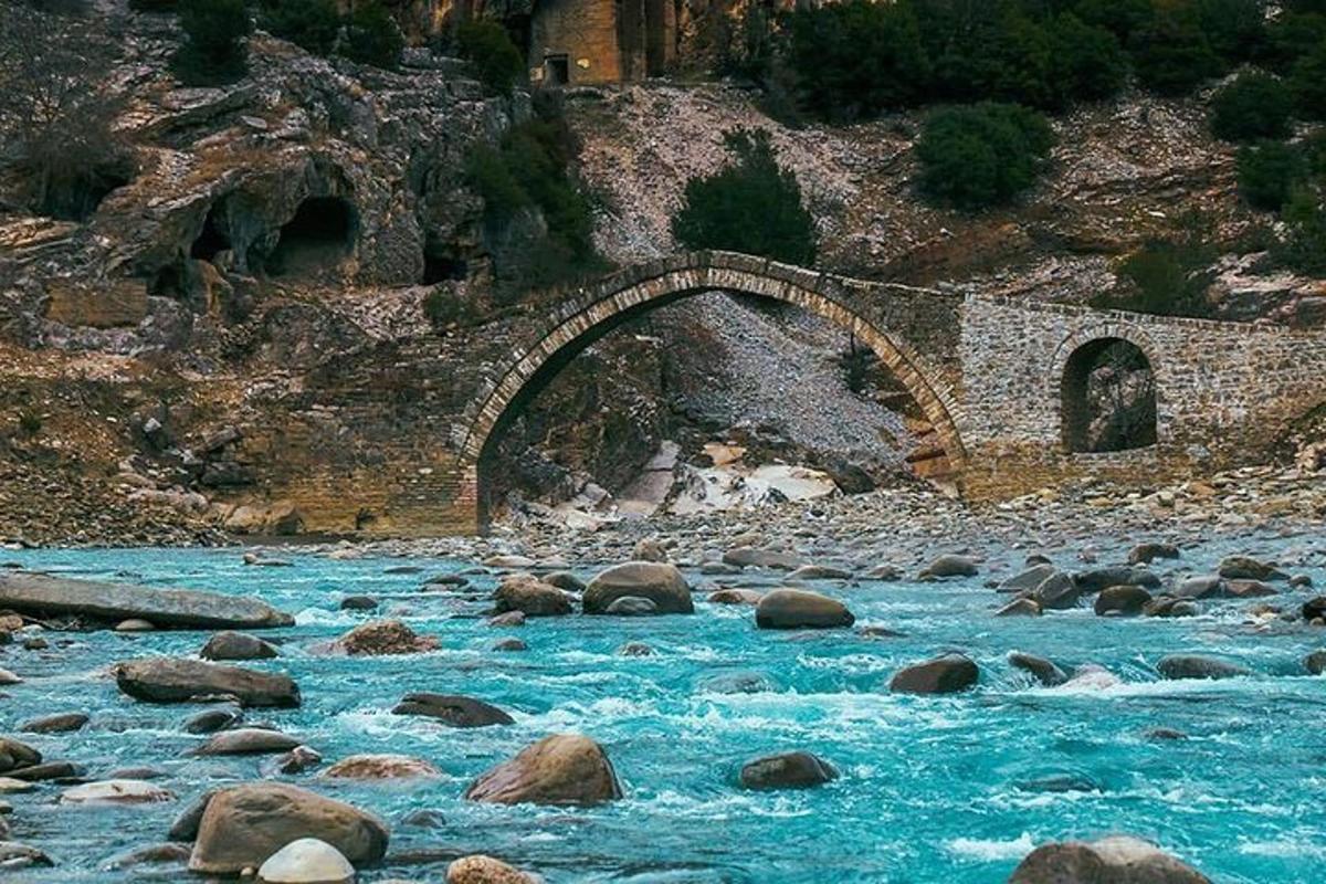 a bridge over a river with rocks on a mountain
