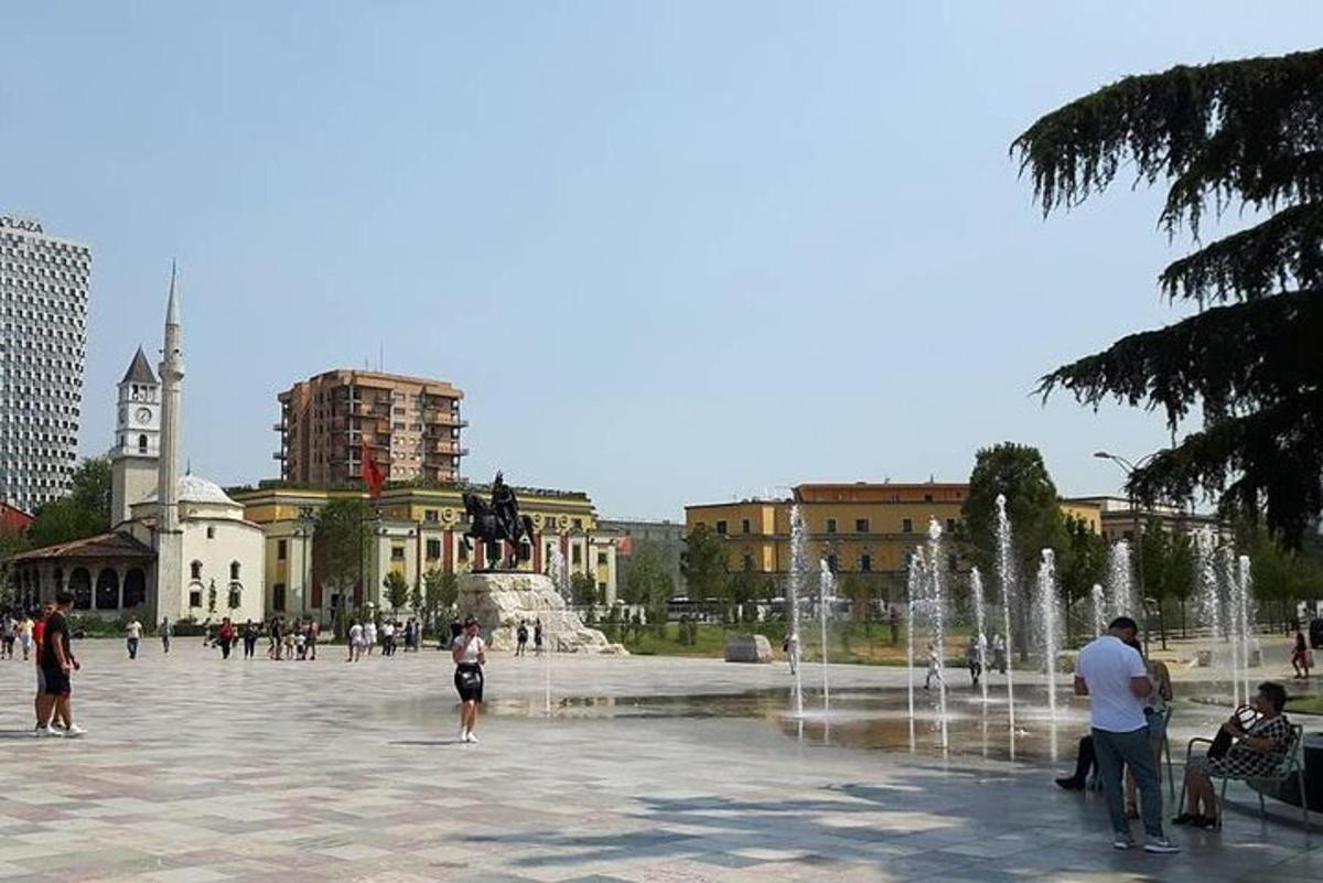 un gruppo di persone in piedi attorno a una fontana in una città