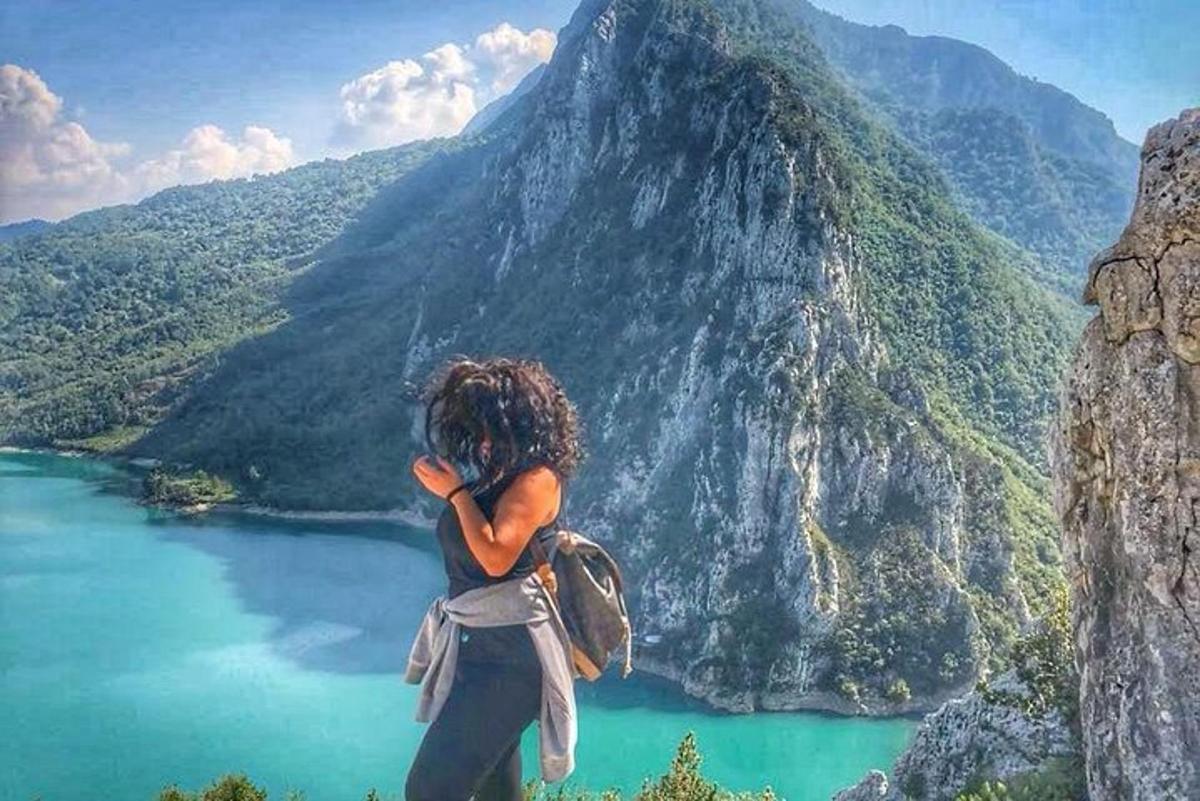 žena stojící na vrcholu hory s výhledem na jezero