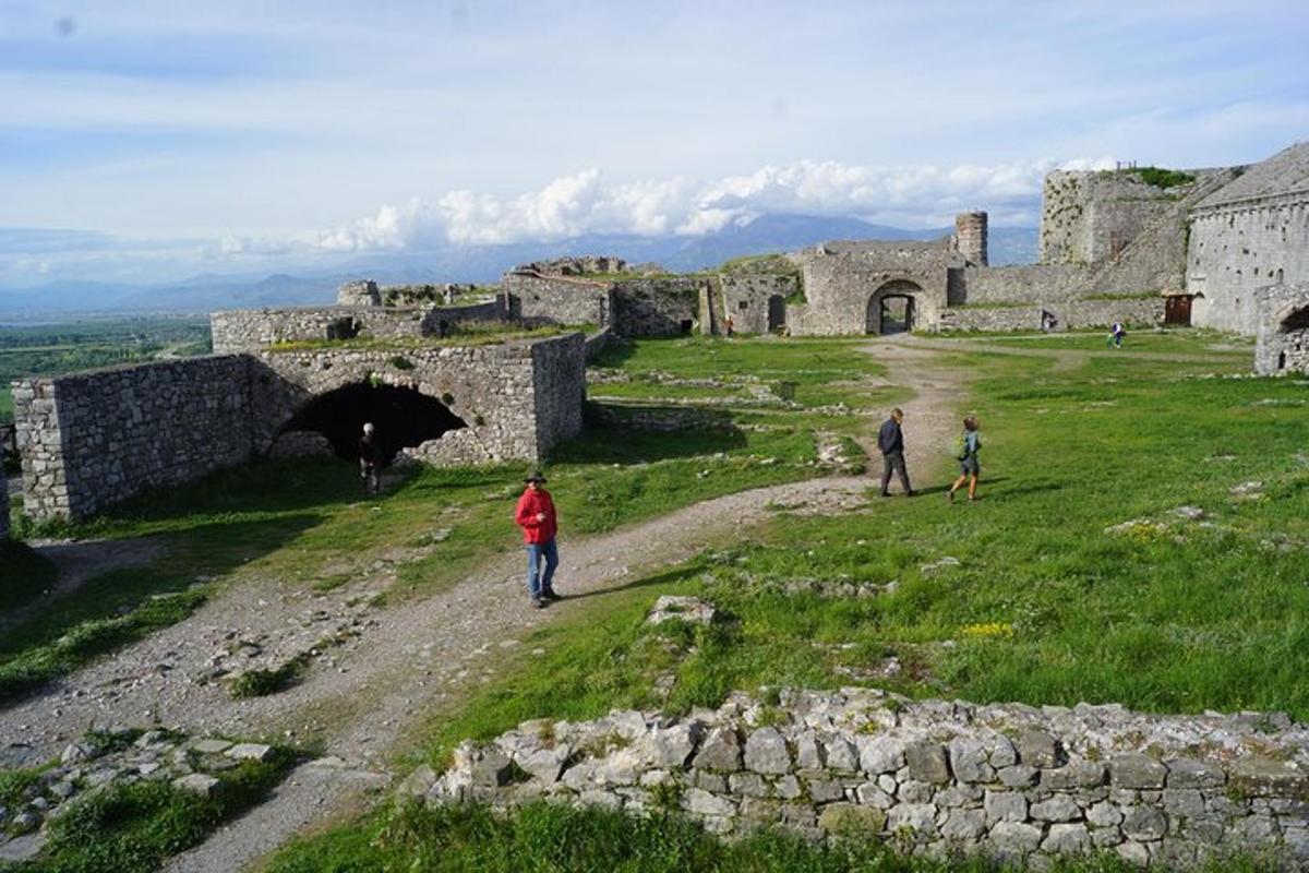 Un grupo de personas caminando por un camino de tierra junto a un castillo.