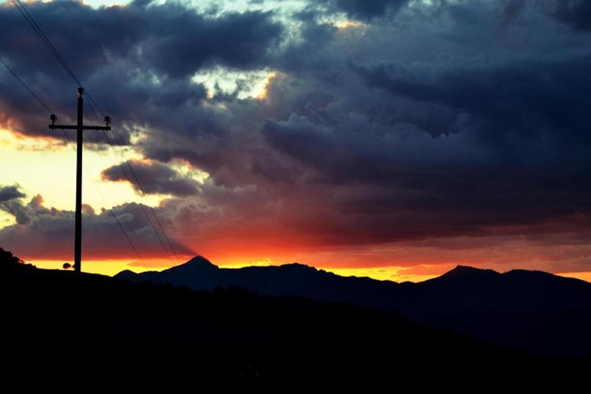 a sunset with a telephone pole and a mountain