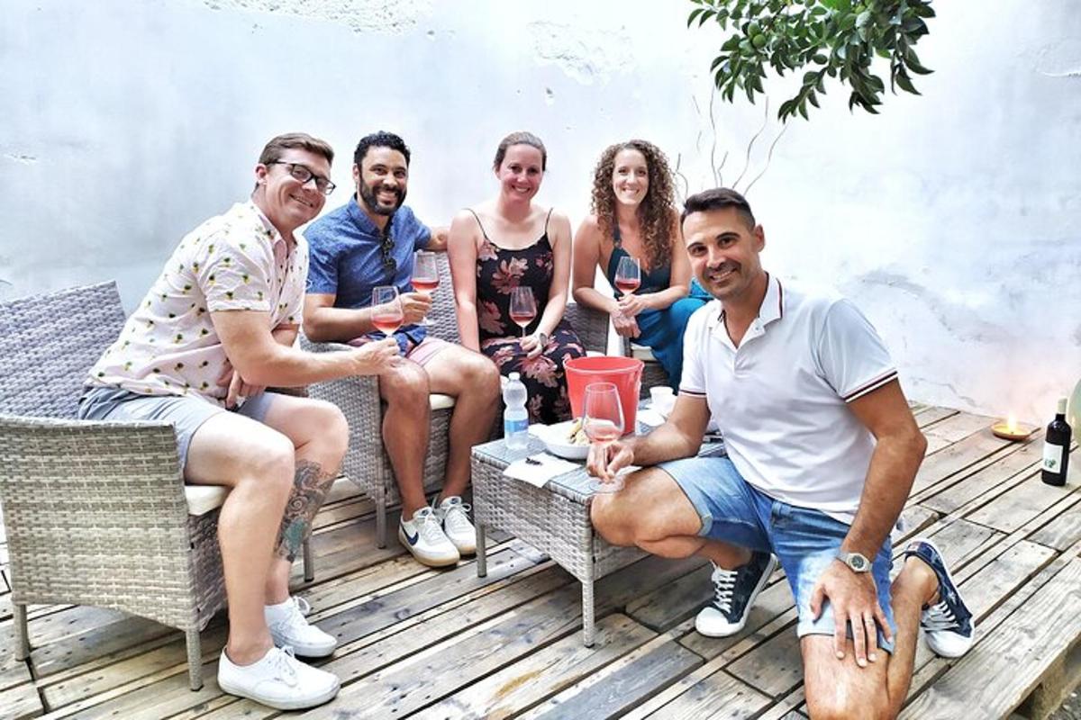 grupp inimesi istub tekil ja joob veini