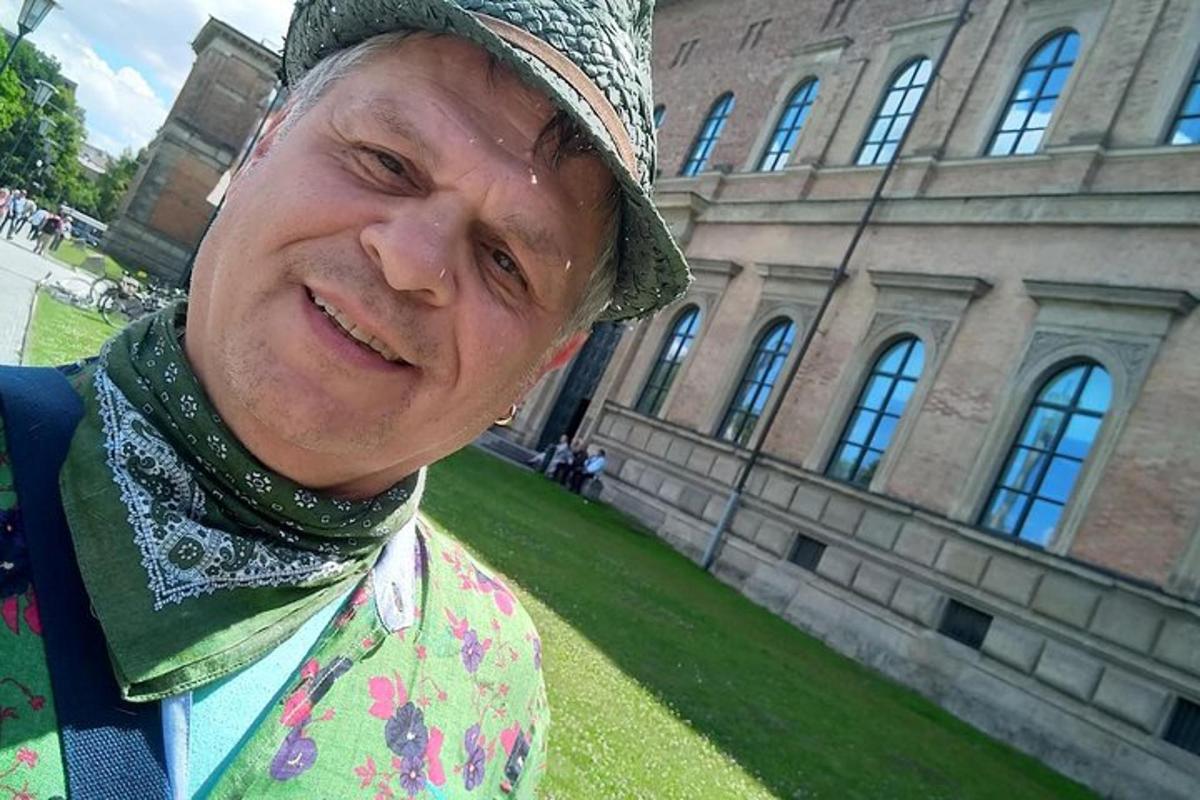 un bărbat mai în vârstă zâmbește în fața unei clădiri