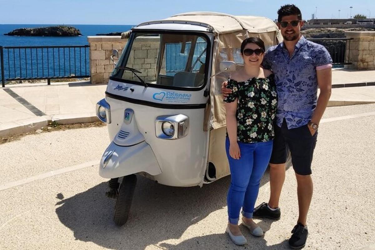 muž a žena stojící vedle malého motorového skútru