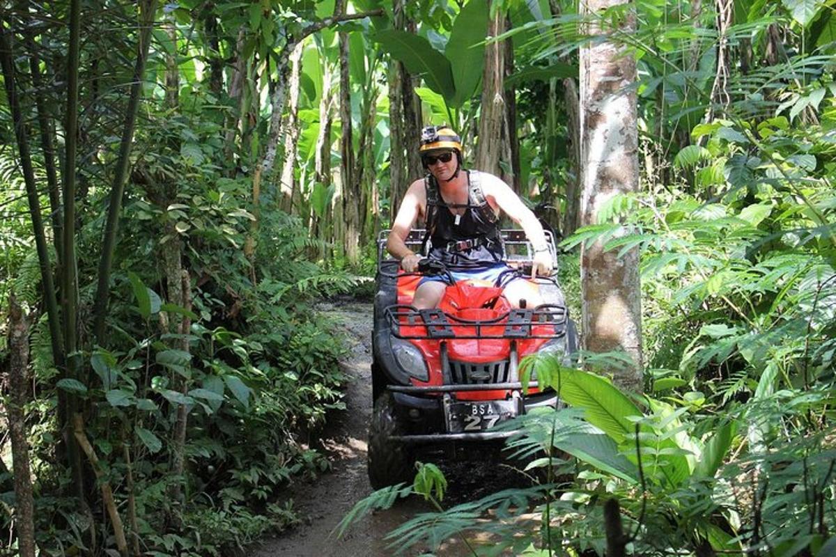 un home conduint un quad per un sender al bosc