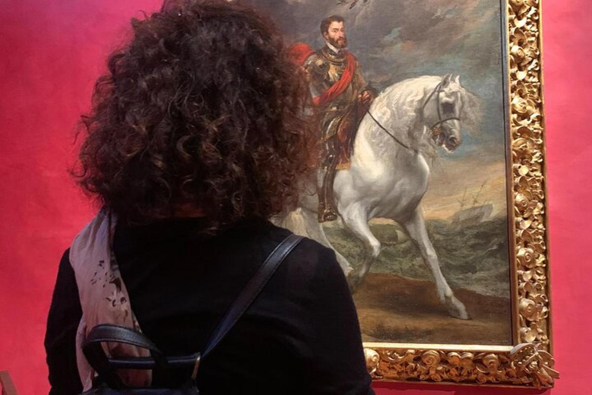Una mujer mirando un cuadro de un hombre montando a caballo.