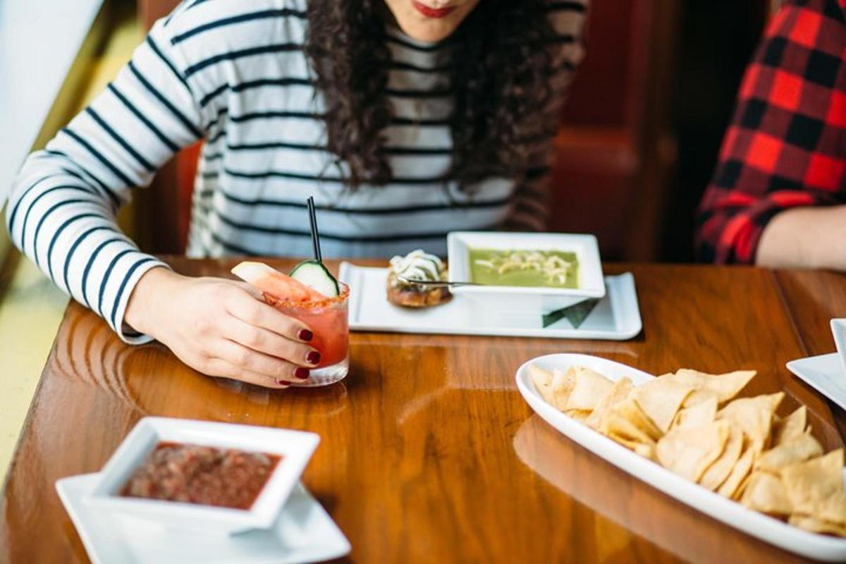 a woman sitting at a table with a drink and chips
