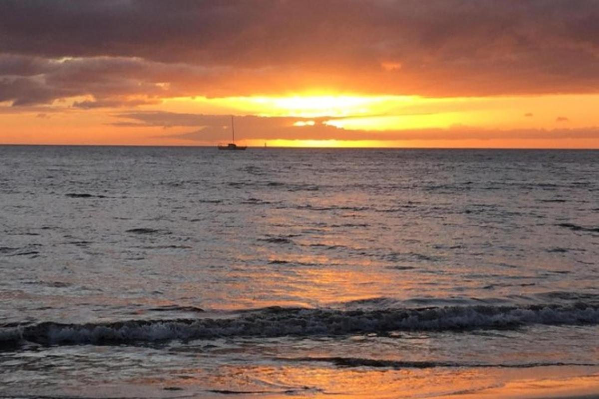 isang paglubog ng araw sa ibabaw ng karagatan na may bangka sa di kalayuan