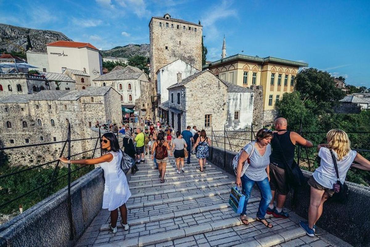 a group of people walking down a bridge in front of a castle