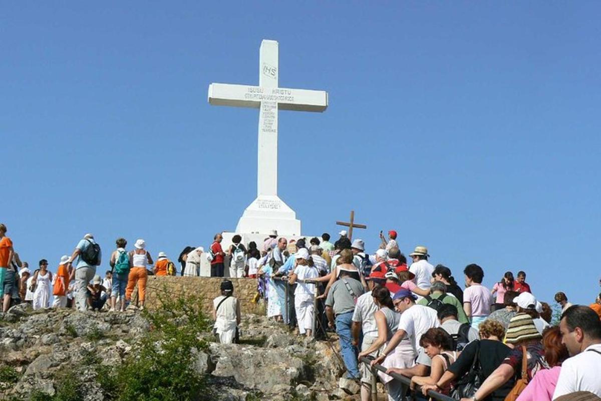 dav lidí stojících kolem bílého kříže