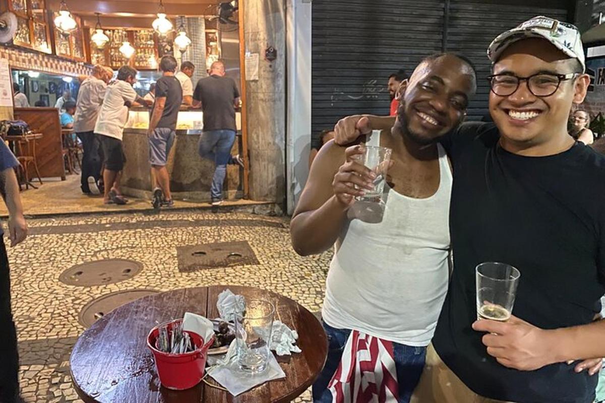 dois homens em pé ao lado de uma mesa com um copo