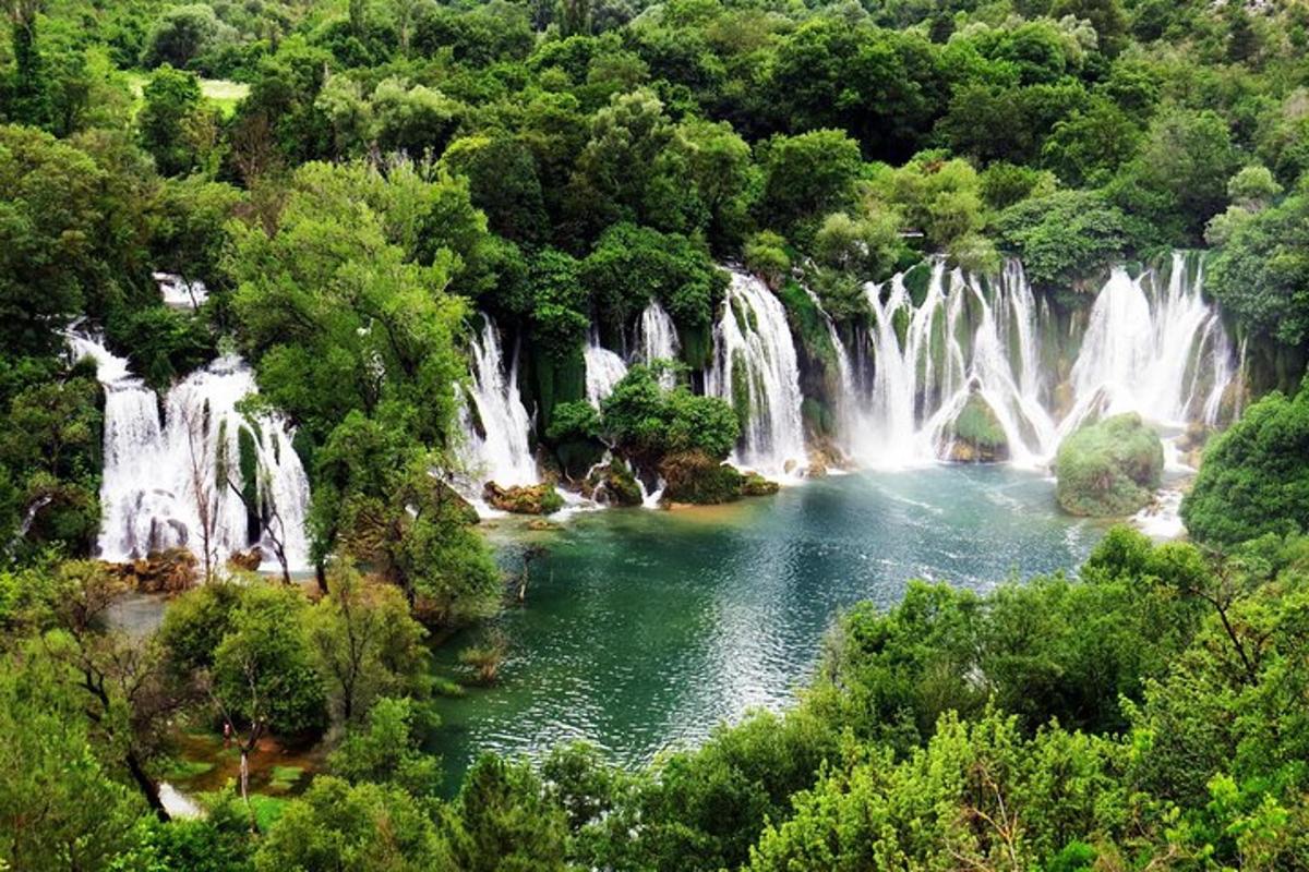 eine Gruppe von Wasserfällen in einem Wald mit einem See