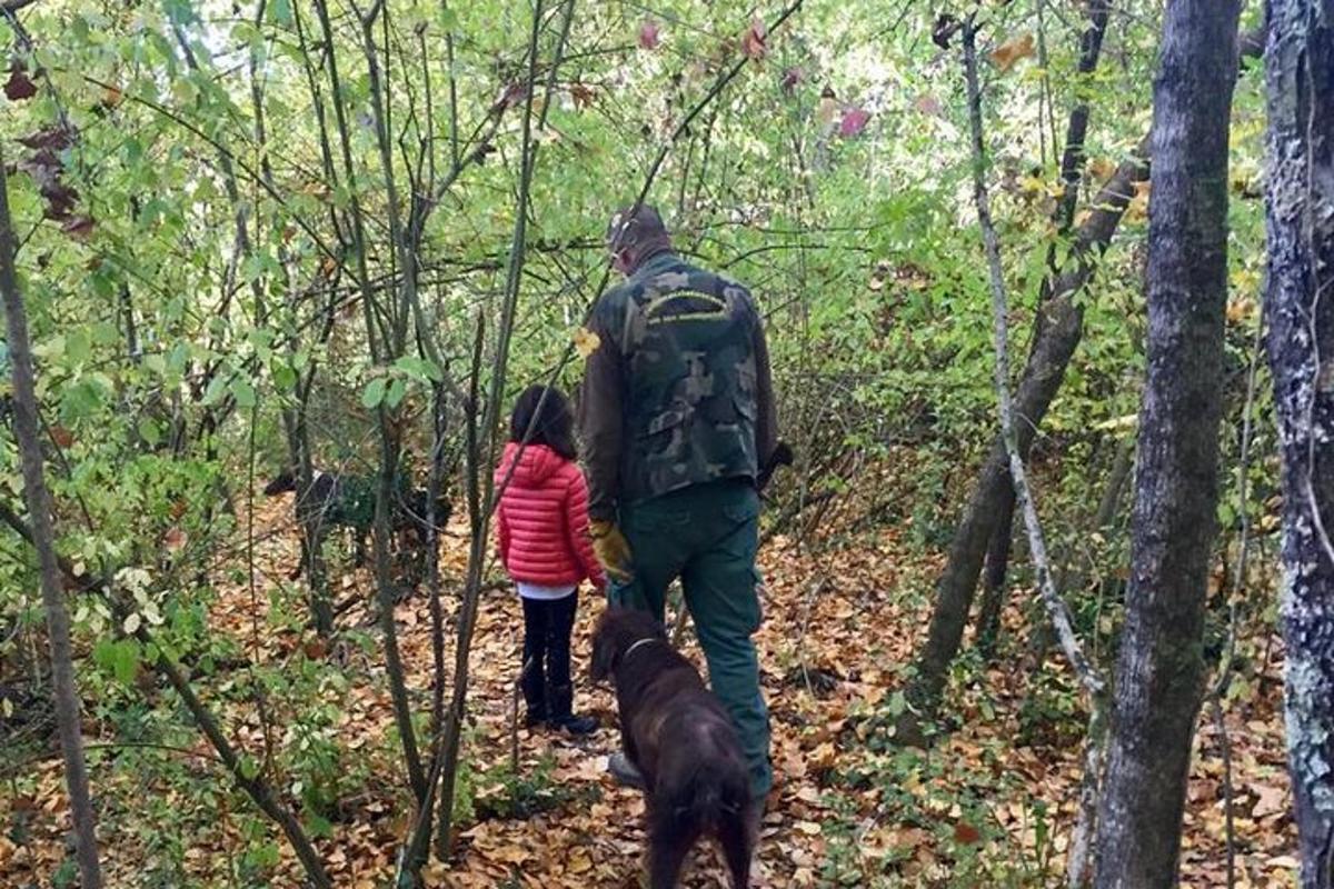 Un hombre, un niño y un perro caminando por el bosque.