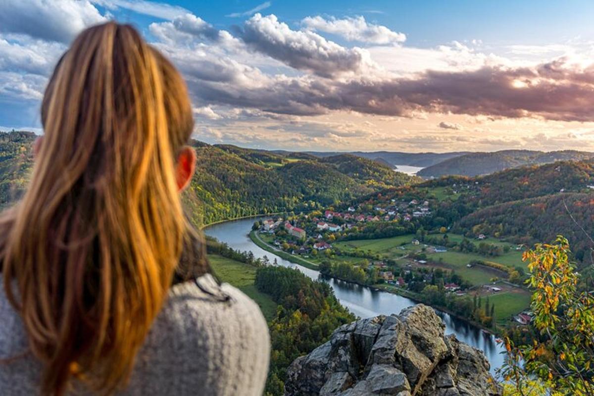 žena stojící na vrcholu hory s výhledem na řeku