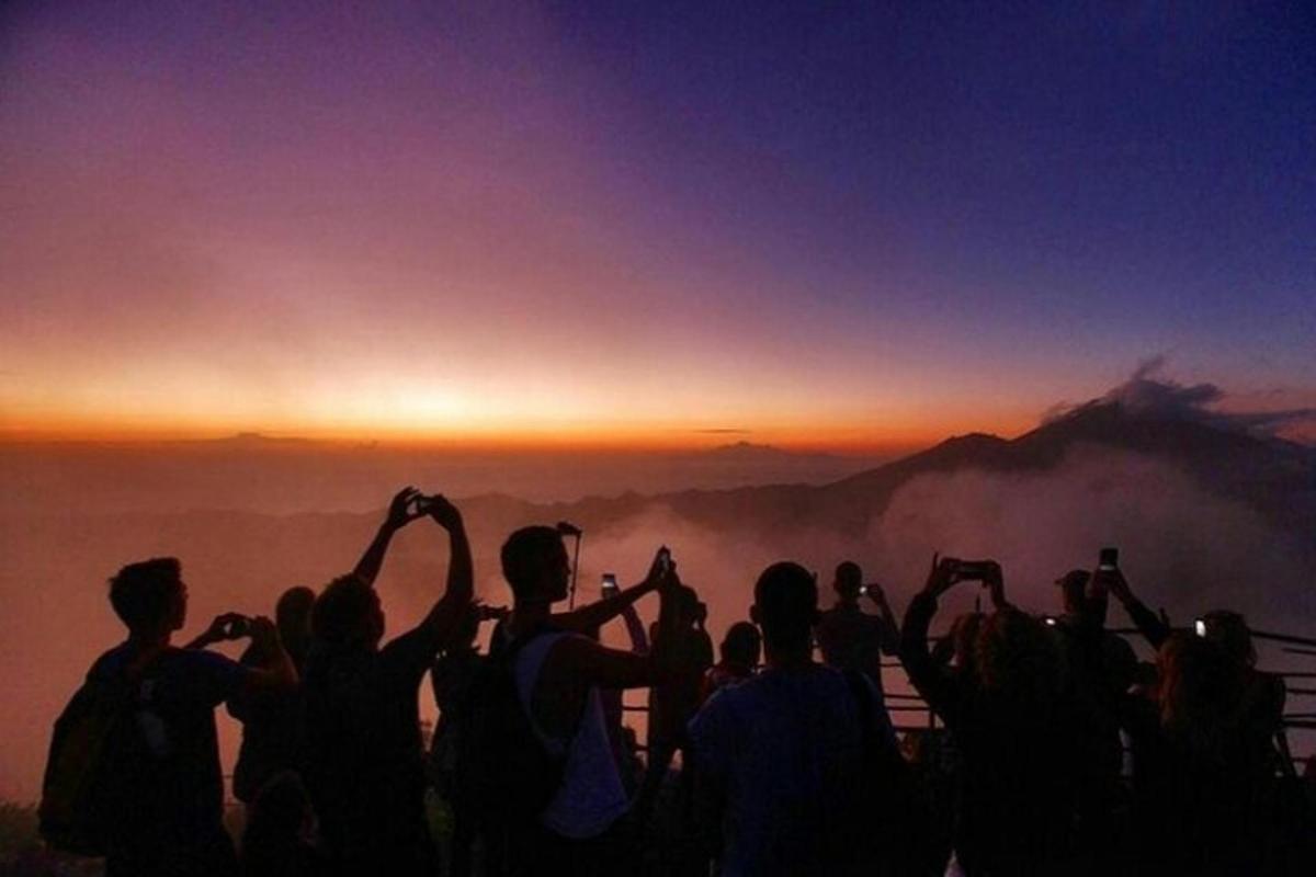 Un grupo de personas de pie en la cima de una montaña al atardecer.
