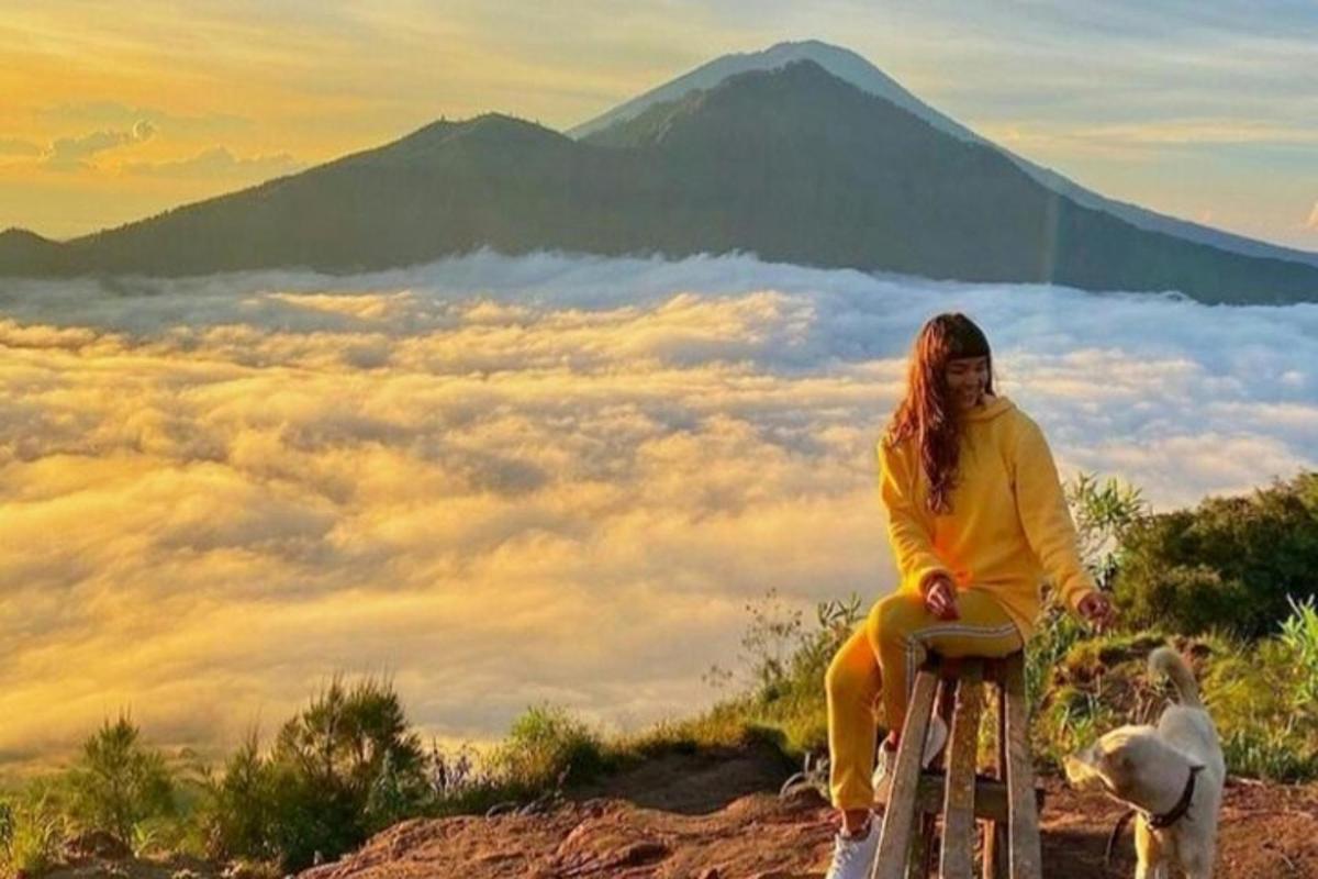 Una mujer sentada en un taburete en una montaña con un perro.