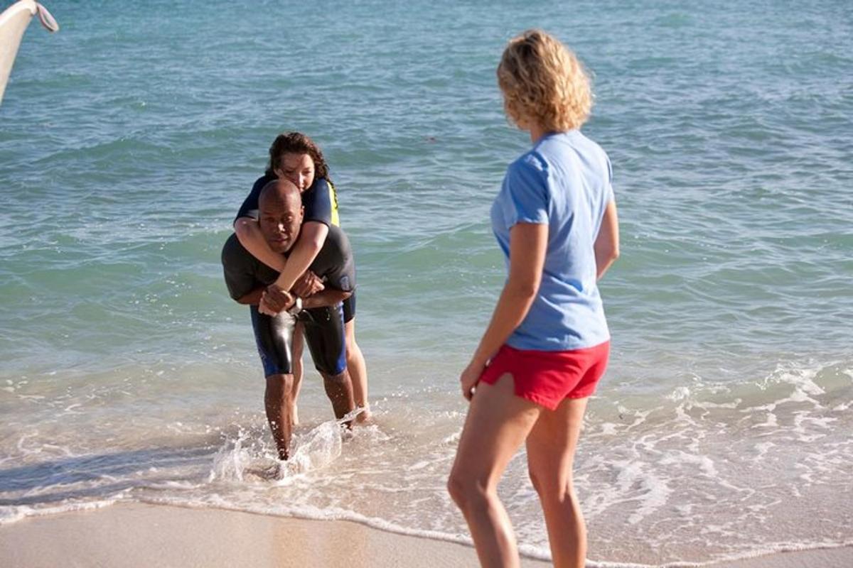 twee vrouwen en een man lopen op het strand