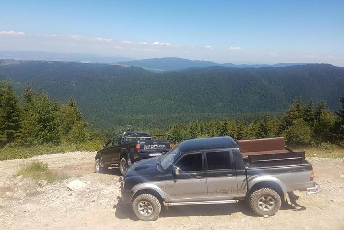 two trucks parked on the side of a dirt road
