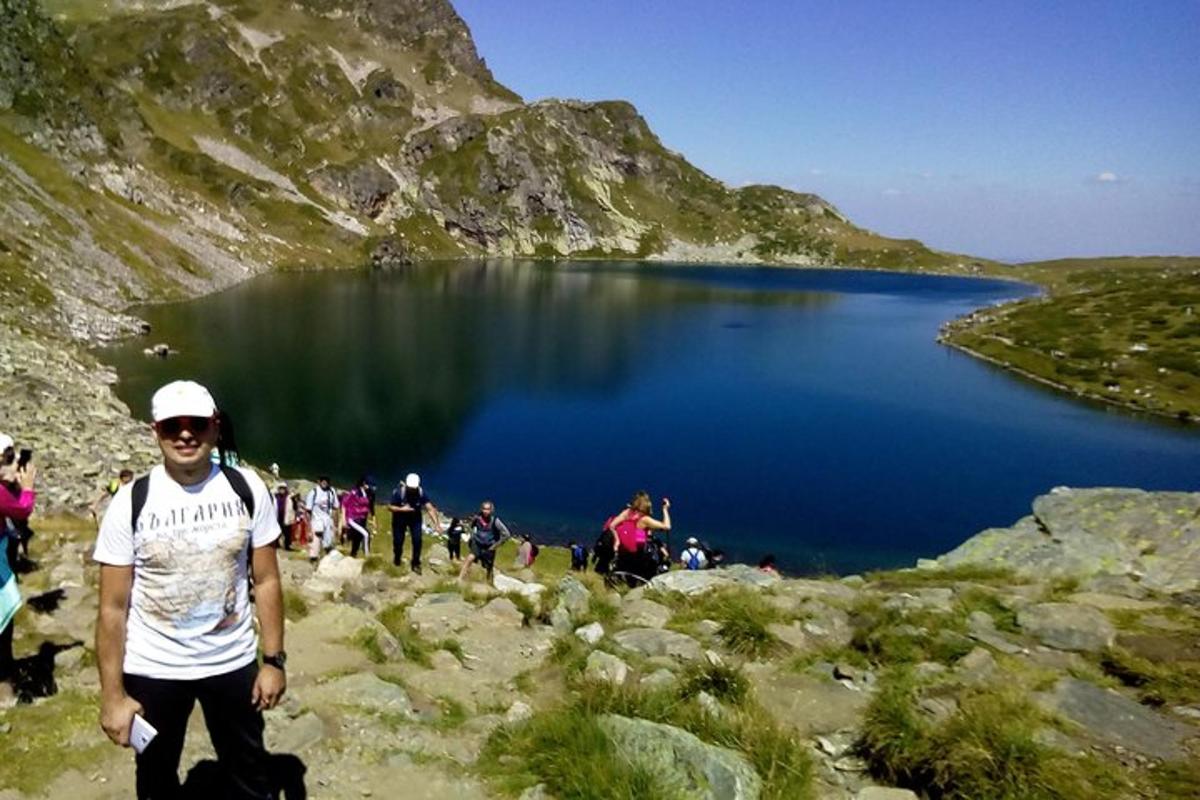 a man standing on top of a mountain near a lake