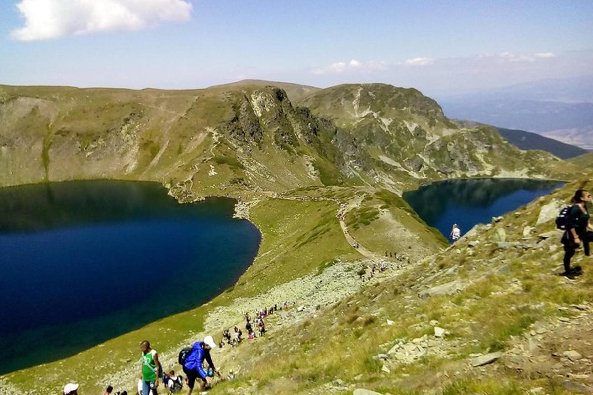 a group of people walking on a hill with a blue lake