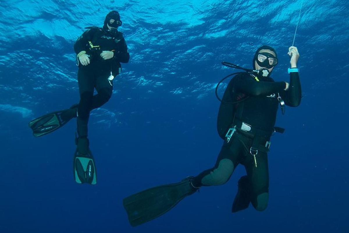 two people in wetsuits are swimming in the water