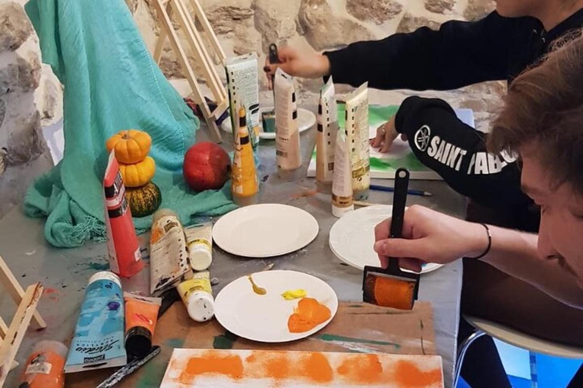 um grupo de pessoas pintando pratos de papel sobre uma mesa