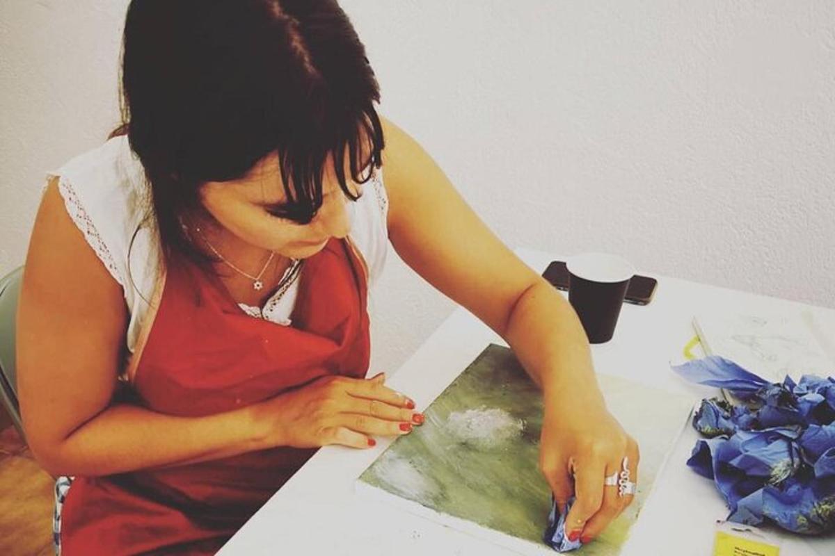 žena sedící u stolu a řezající kus papíru